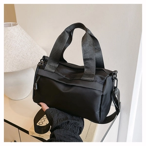 Detalle del bolso bandolera de nailon negro con textura satinada y asa tejida