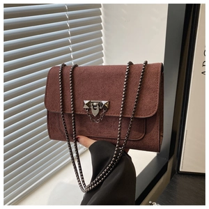 Détail du sac à rabat en daim rouge-brun avec fermoir et chaîne gris anthracite