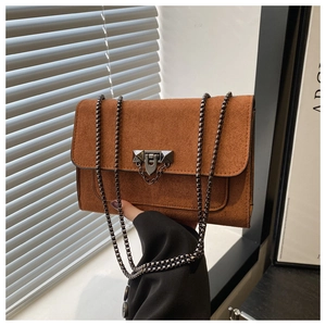 Détail du sac bandoulière en daim marron avec finition mate et boucle en métal noir