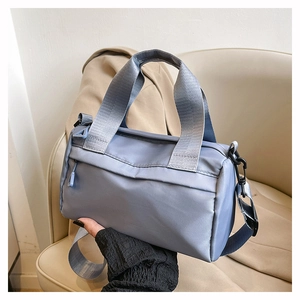 Detalle del bolso bandolera azul claro en nailon con asa ancha y gancho metálico