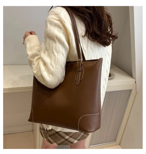 Detail van bruine leren shopper met witte contraststiksels en een lange schouderband