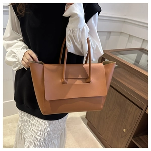 Detail of caramel leather tote bag with unique flap-through handle design for work