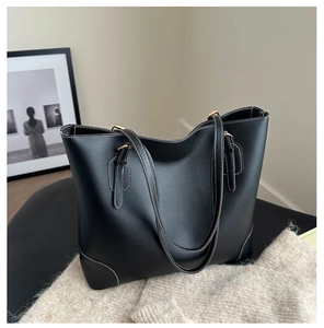Detail van zwarte leren tas met witte contraststiksels en goudkleurige metalen hardware