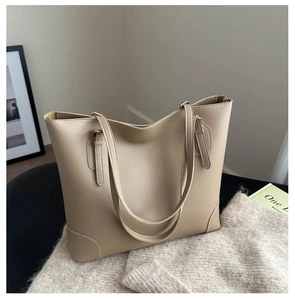 Detail van beige kunstlederen tote bag met fijn stiksel op een zachte gebreide ondergrond