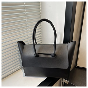 Detail der minimalistischen schwarzen Tote Bag mit Litschi-Textur und langen Tragegriffen