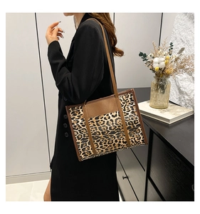 Close-up of leopard print tote bag with brown leather handles worn by a model