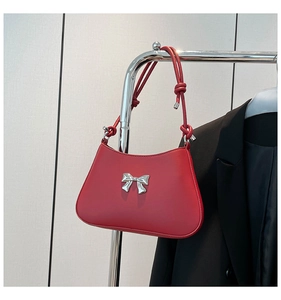 Détail du sac rouge sous l'aisselle avec nœud argenté et bandoulière nouée