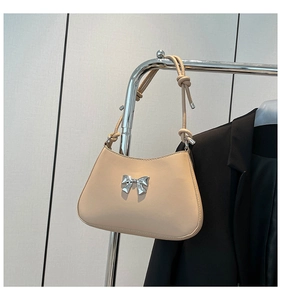 Vue détaillée du sac croissant beige avec boucle nœud argentée et bandoulière à nœuds