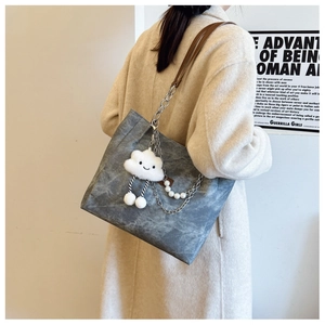 Detail of tote bag with metal chain, pearl charm, and white cloud plush pendant