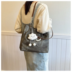 Detail of dark grey canvas tote with brown straps, metal chain, and cute cloud charm