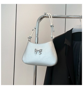 Détail de nœud argenté sur un sac à bandoulière en croissant avec cuir synthétique