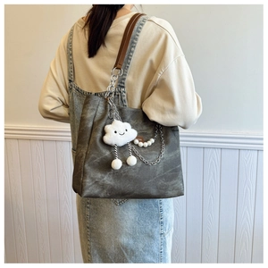 Detail view of charcoal grey canvas tote bag with silver chain and plush cloud charm