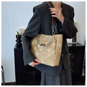 Detail of beige tote bag with pearl chain and fashion leather tag on grey blazer