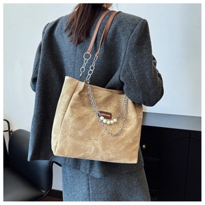 Detail of fashion tote bag with silver chain, brown leather handles and pearl accents