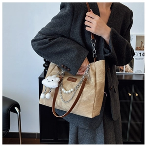Detail of khaki tote bag with silver chain, pearl charm, and white cloud plush pendant