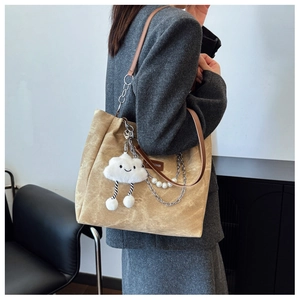 Detail of beige tote bag with pearl chain strap and cute white plush cloud charm accessory