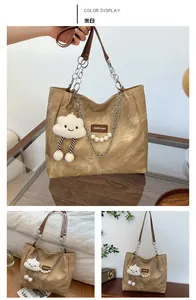 Detail of cream white tote bag with silver chain strap and cloud plush pendant accessory