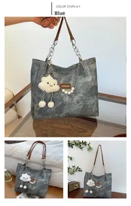 Detail of blue denim tote bag with leather chain strap and cloud plush charm decoration