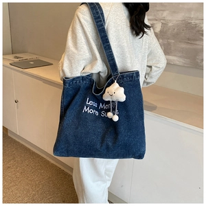 Detail van de donkerblauwe denim shopper met wit borduursel en zachte wolkenhanger