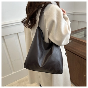 Detail of a dark brown large tote bag showing soft leather texture and casual shoulder carry