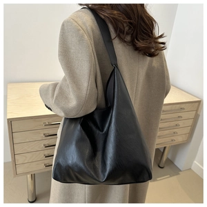 Side view of a large black leather hobo shoulder bag styled with a wool coat