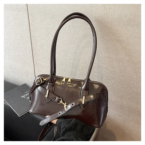 Détail de la texture en cuir ciré marron foncé et ferrures dorées du sac à main
