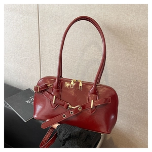 Détail macro du sac à main bordeaux brillant avec fermetures dorées et boucle en cuir