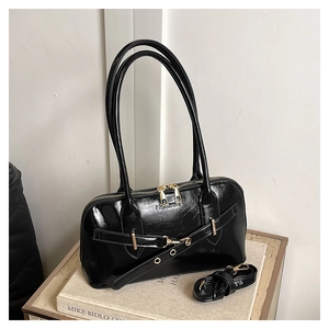 Détail du sac à bandoulière noir brillant avec zips dorés et texte fashion embossé