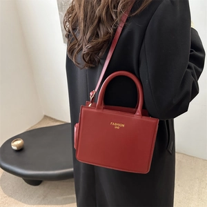 Borsa a mano squadrata minimalista in pelle rossa con scritte dorate per look eleganti