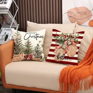 Set di due federe natalizie per cuscini decorativi su un divano in tessuto beige