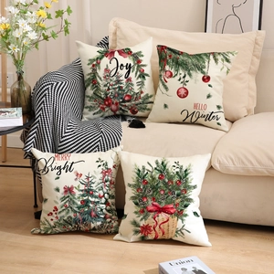 Lot de quatre housses de coussin de Noël en lin avec motifs festifs sur un canapé beige