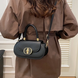Borsa a tracolla francese in pelle nera con fibbia dorata su un cappotto marrone