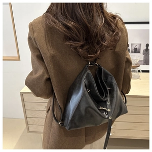 Détail d'un sac à dos en cuir noir souple avec fines bretelles et boucles en métal