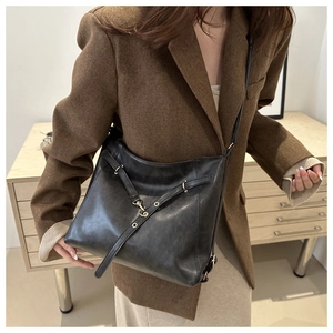 Détail du sac bandoulière vintage noir avec lanières croisées et ferrures dorées