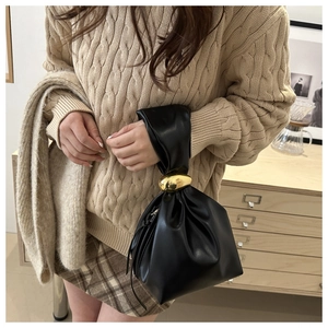 Détail du sac seau noir plissé en cuir avec une grande boule en métal doré sur la poignée