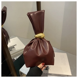 Détail du sac seau en cuir bordeaux avec sa boucle décorative en métal doré ovale