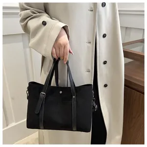 Detail view of the black suede bucket bag with leather handles and matte silver hardware
