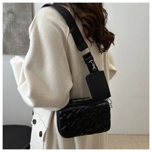 Detail of black quilted crossbody bag with stylish detachable mini pouch and wide strap