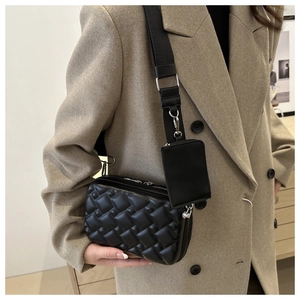Close-up of black woven leather crossbody bag featuring a small detachable pouch on strap