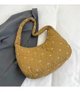 Detailaufnahme der gelben Stepptasche mit weißem Schleifenmuster und breitem Gurt