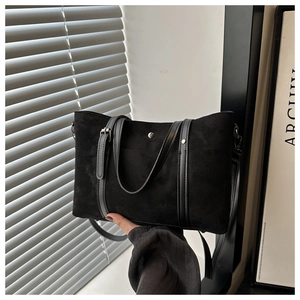 Detail showing matte black tote bag with silver studs and smooth synthetic leather handles