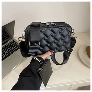 Detail of black crossbody bag featuring textured quilted pattern and small pouch attachment