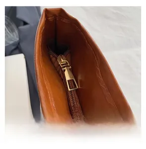 Detailed close-up of a smooth gold-tone zipper on a brown leather minimalist tote bag