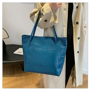 Macro view of bright blue crocodile pattern tote bag showing glossy leather texture