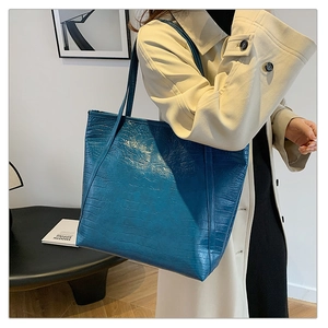 Close-up of deep blue crocodile-embossed tote bag featuring premium leather texture