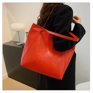 Close-up of red crocodile-patterned tote bag showing texture and slim shoulder strap