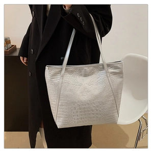 Detail of silver crocodile pattern tote bag showing texture and slim shoulder straps