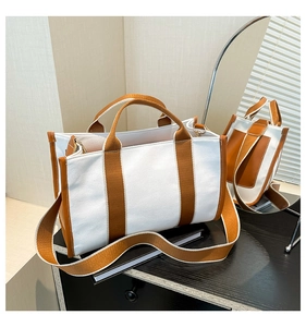 Detail of white canvas tote bag with brown leather trim and adjustable wide shoulder strap