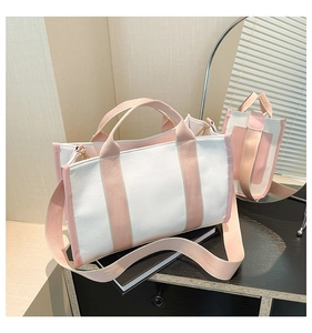 Detail of canvas tote bag with pink trim, wide shoulder strap and gold-tone metal hardware