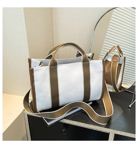Detail of canvas tote bag with brown trim on a decorative cabinet in a modern room